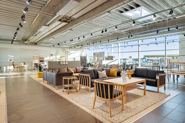 Store møbelforretning med træmøbler og lædersofaer, samt lyse loftslamper og gulvtæppe