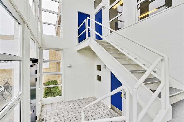 Moderne lobby med hvide vægge, hvide trapper og blå døre, der fører til de øvre etager og smukke glasruder med udsigt til