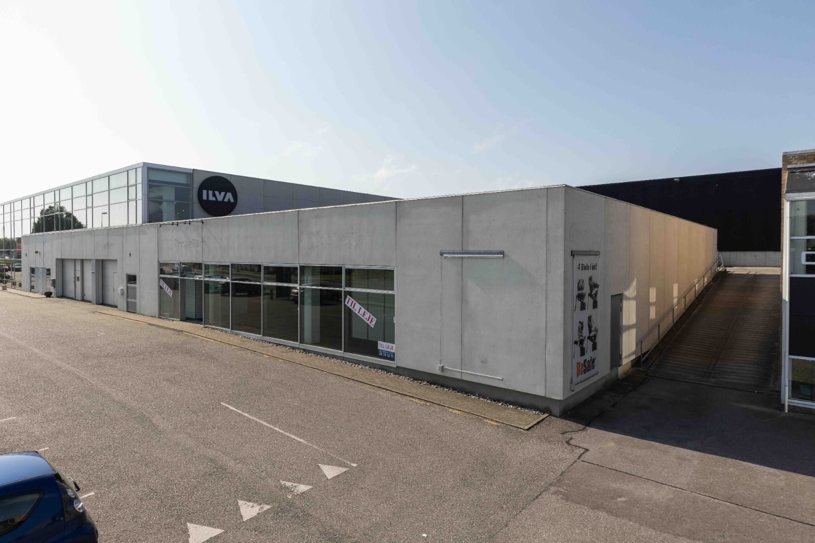 En stor hvid bygning med flere vinduer og indgange og skilte med navnet ILVA og BeSafe