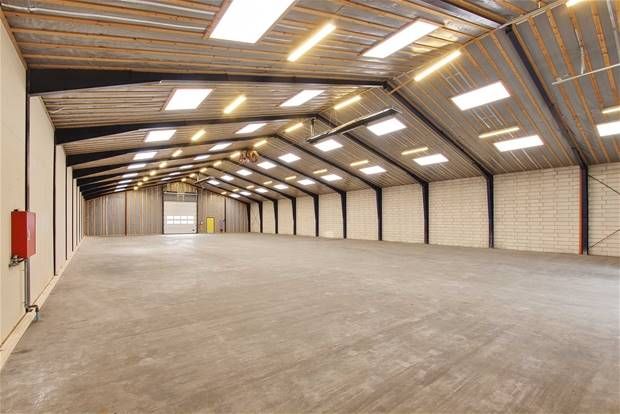 Ledig lagerhal med højloft og gulv til leje. Moderne lyssystem og rødt ildslukker. Størrelsen er 850 kvm og lejes i moduler