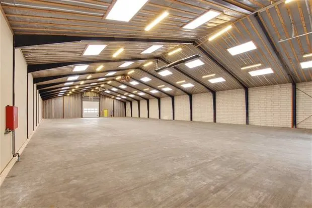 Ledig lagerhal med højloft og gulv til leje. Moderne lyssystem og rødt ildslukker. Størrelsen er 850 kvm og lejes i moduler