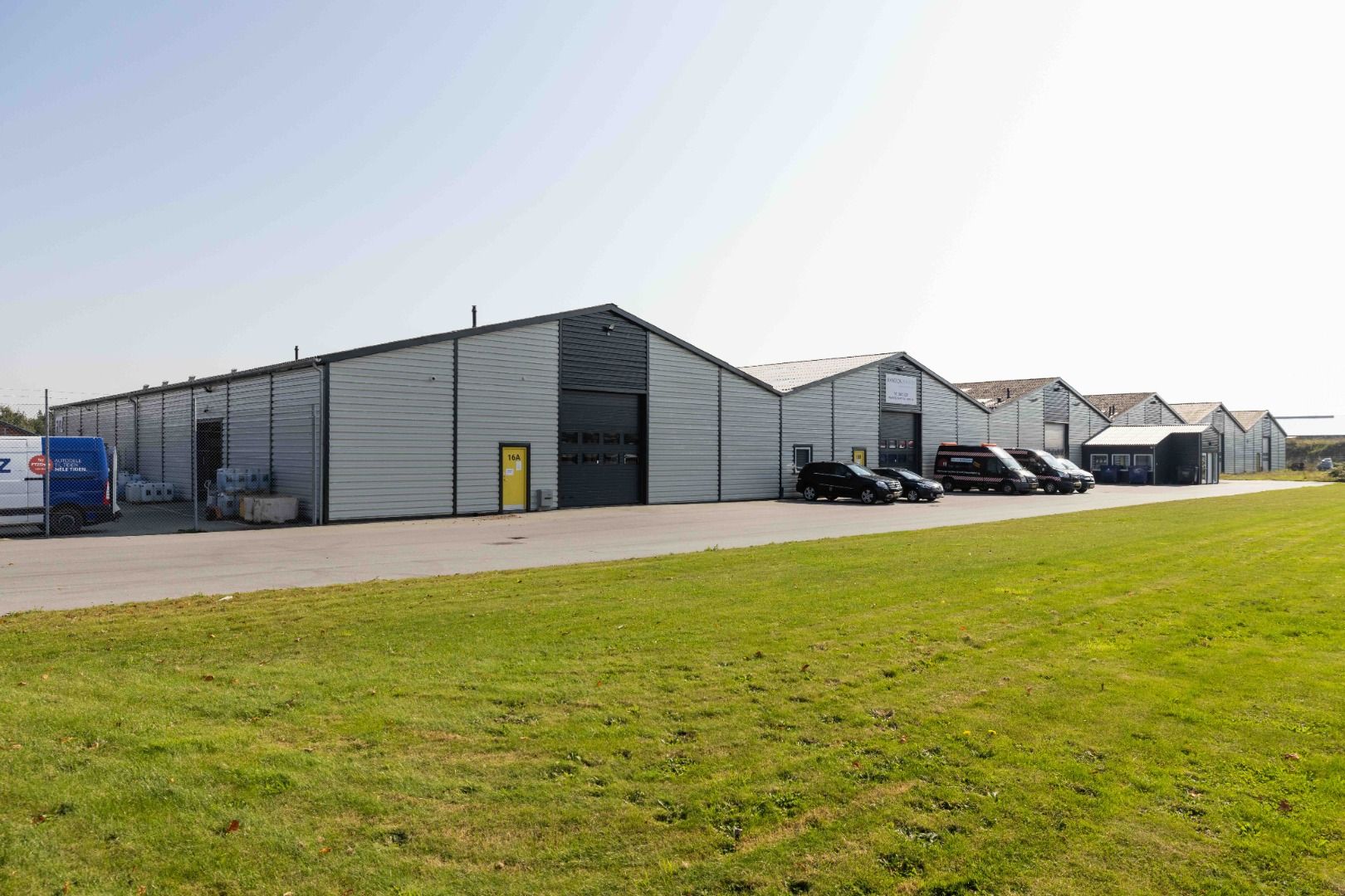 Lagerhal i moduler á 42 kvm op til 850 kvm lagerareal. Flere moduler står rækkevis. Parkeringsplads med biler og en