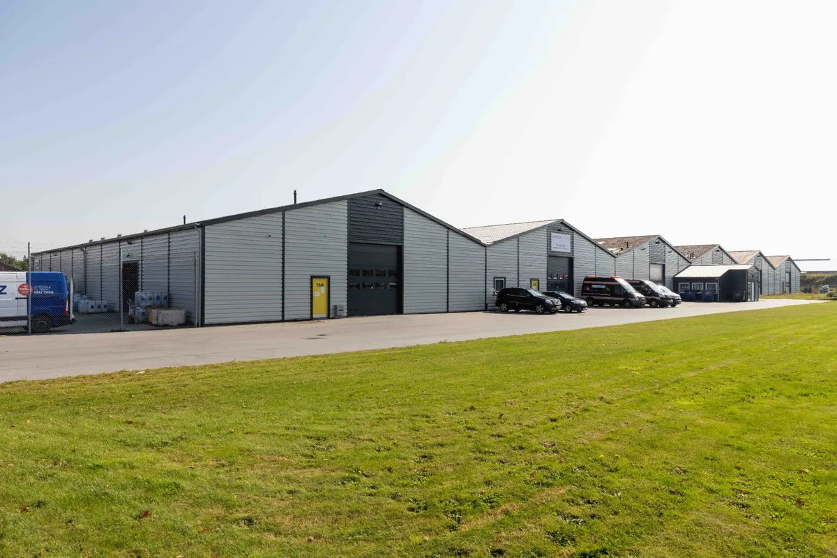 Lagerhal i moduler á 42 kvm op til 850 kvm lagerareal. Flere moduler står rækkevis. Parkeringsplads med biler og en