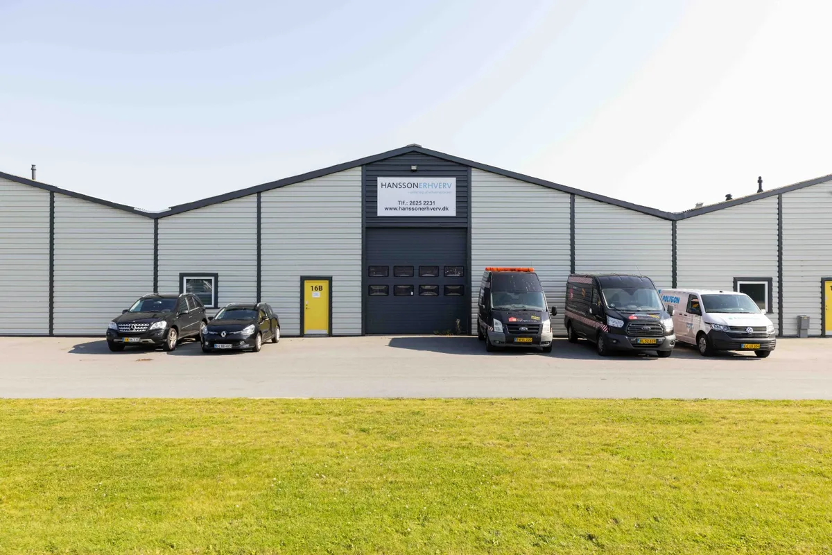 Foran et stort lager er der parkeret fem køretøjer og der er en dør med nummeret 16B på