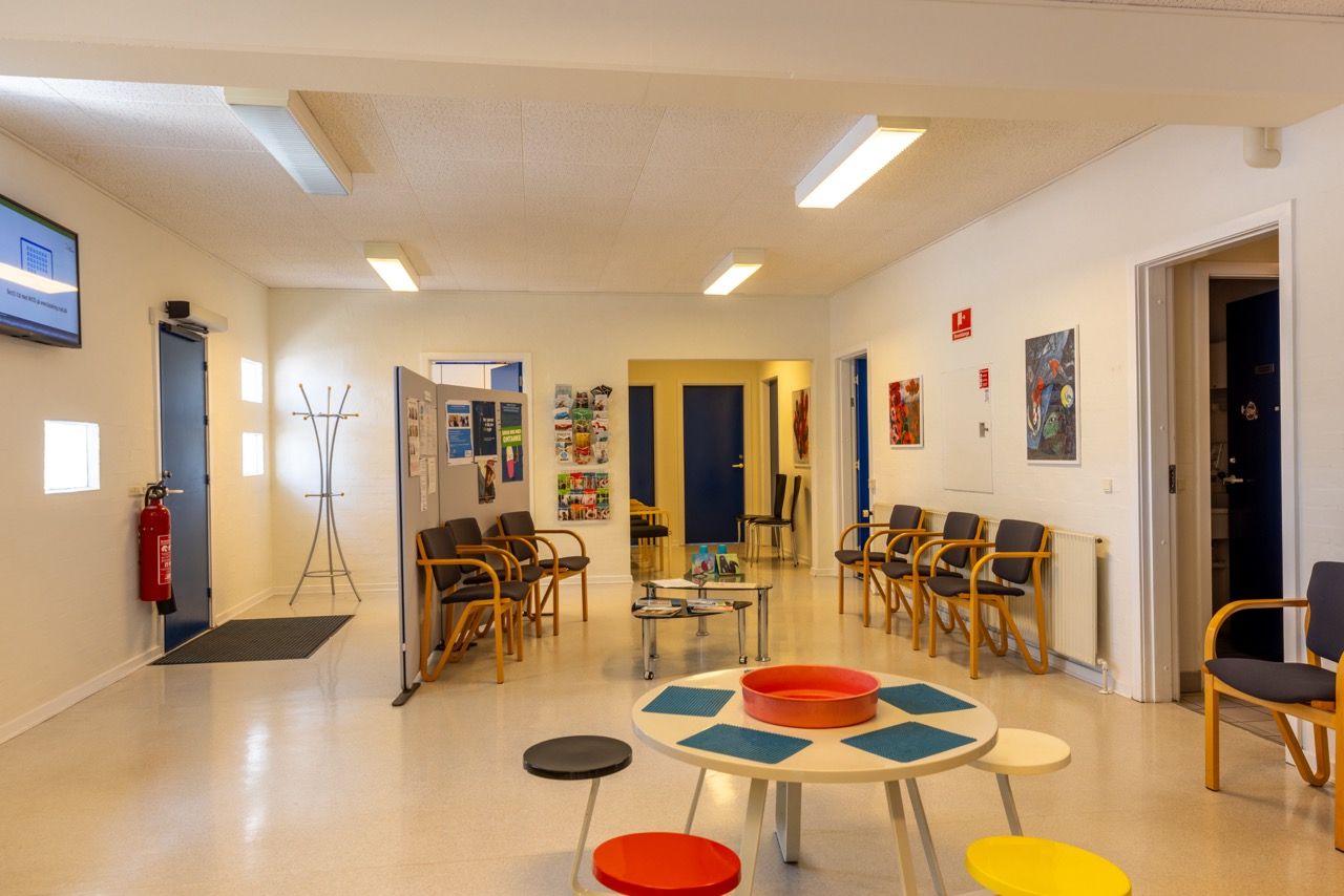 Moderne lyse lokaler med nye gulve og nymalede overflader, fire stole, og en rund tabel med en skål i midten