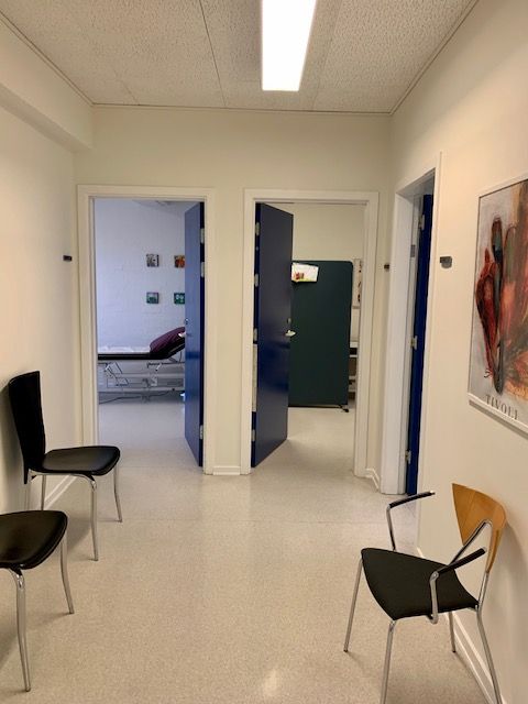 I en sundhedsklinik med moderne lokaler og hvide vægge samt lyse gulve og tre stole