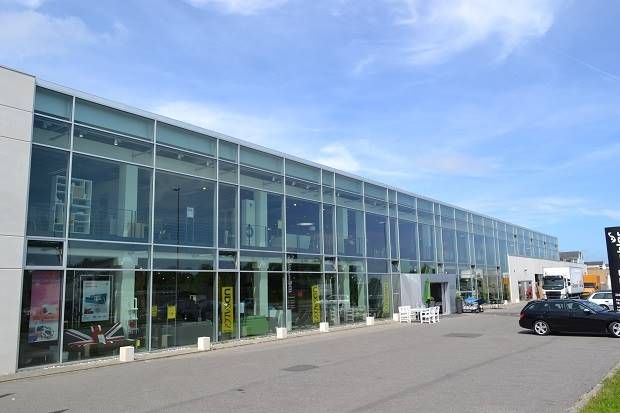 Store glasvinduer, gulve og vægge samt tekst på facaden, der læses Unison