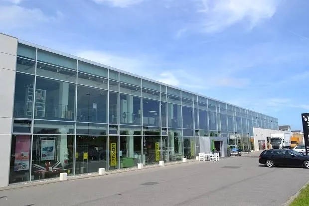 Store glasvinduer, gulve og vægge samt tekst på facaden, der læses Unison