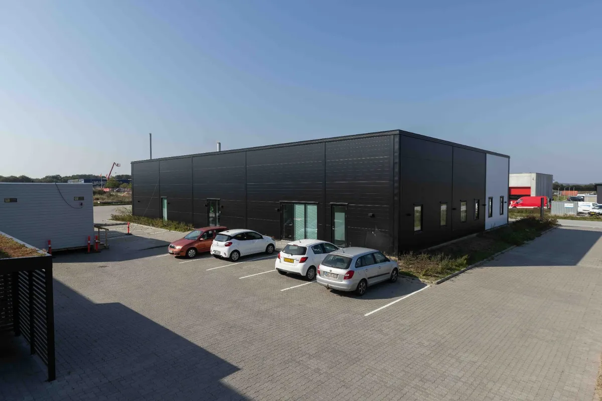 Fire biler parkeret foran et sort bygning, der sandsynligvis er en lagerbygning