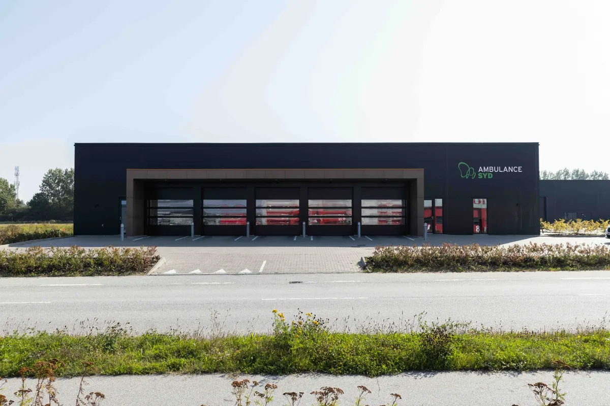 En moderne ambulancestation med store, høje garagedøre og en skrånende taglinje, der afslutter bygningens moderne design