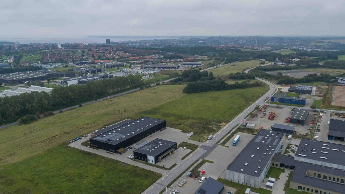 Nybygget produktionsanlæg med solceller på taget og en stor vej foran bygningen