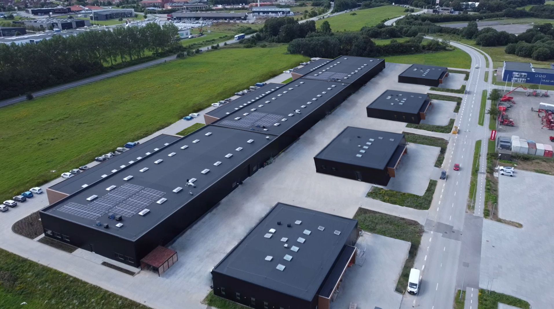 Bygninger med solpaneler på tag og biler parkeret i forgrunden på en parkeringsplads