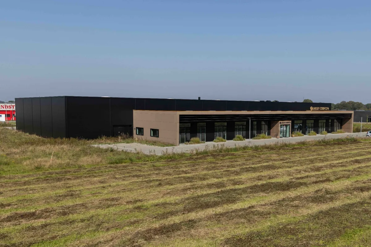 Bygning med moderne design, stående i et åbent område med græs og en vej foran