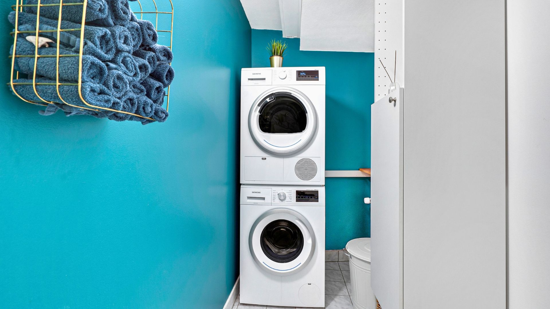 Siemens tørretumbler og Siemens vaskemaskine placeret i et lille værelse med blå væg og en hvid toiletkasse