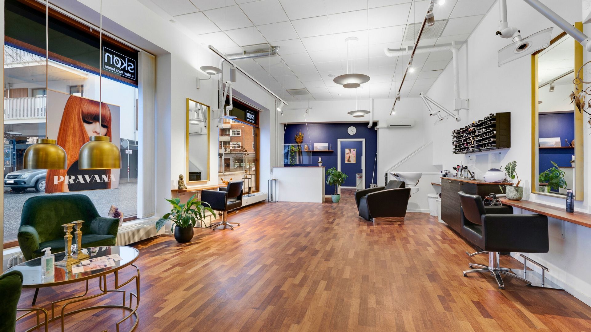 Et moderne indretningsfirma med højt loft og lysegule vægge, møbler, plante og hårsalong med stol, hårvask og spejl