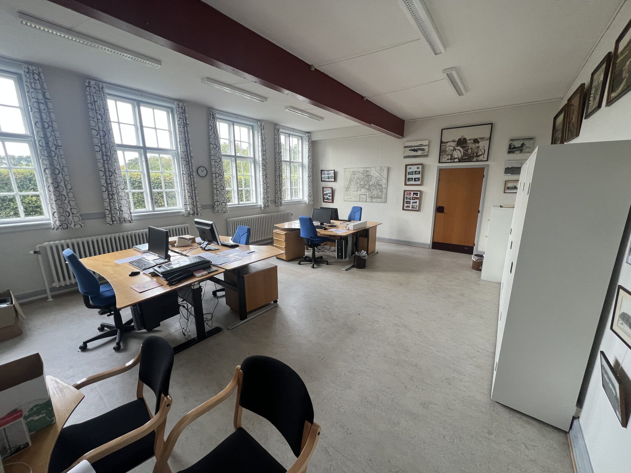 En stor kontor med flere borde og skriveborde samt flere skrivemaskiner og computere