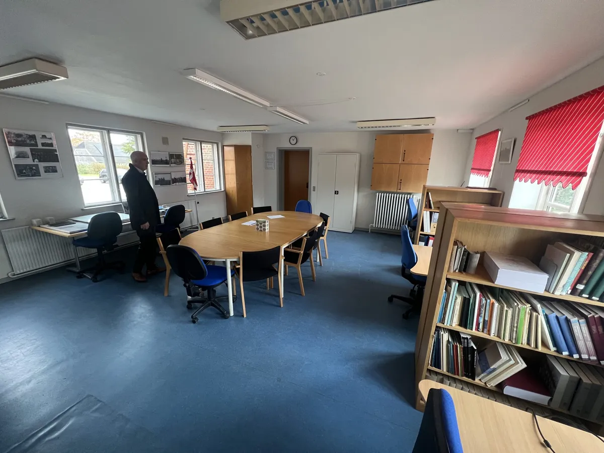 En tom kontorlokal med runde borde og stole, samt en lille biblioteksskranke og gulvbelægning