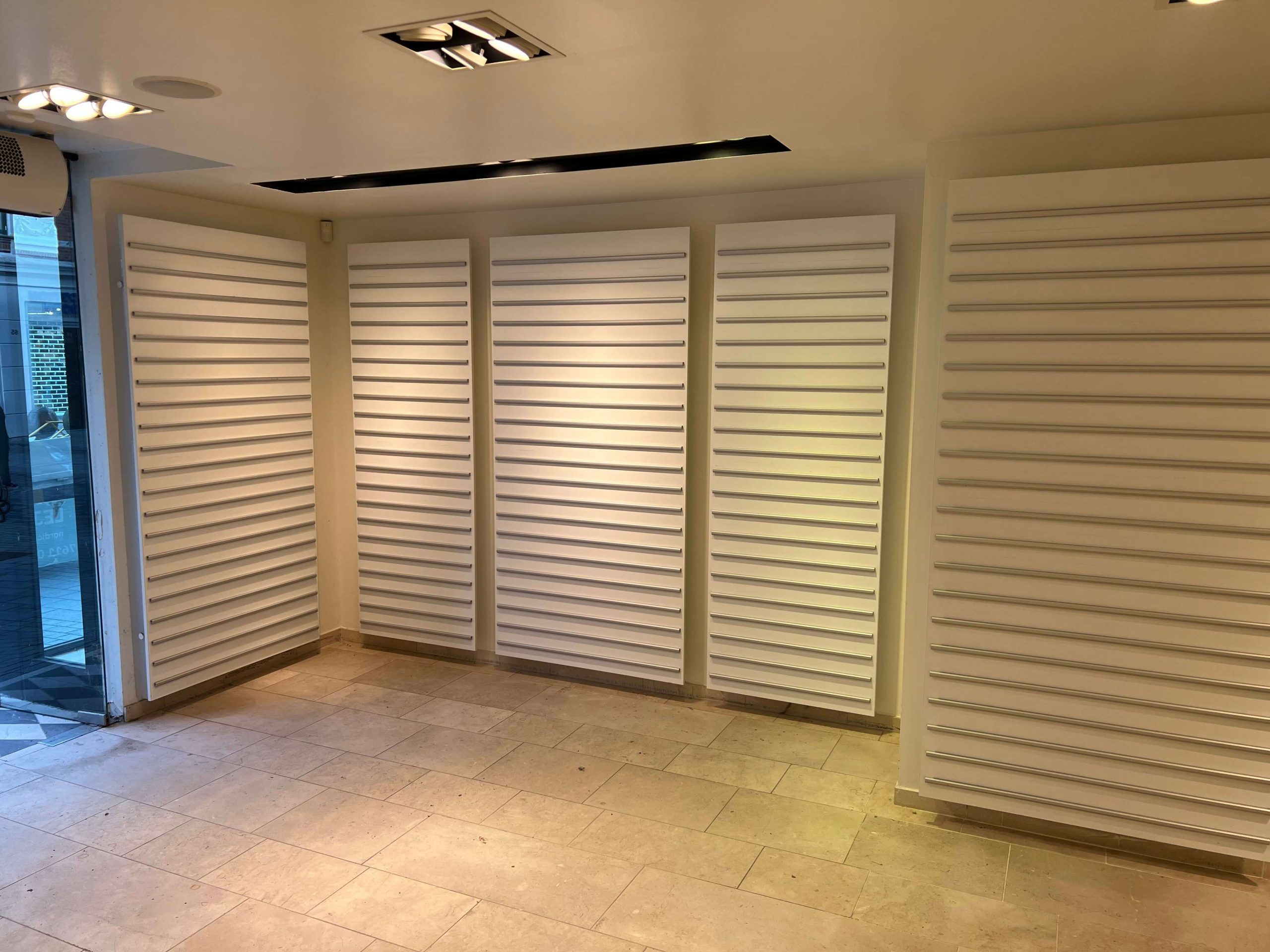 En stor og stilfuld showroom med hvide vægge og møbler, lysegule gulv og loftslampe