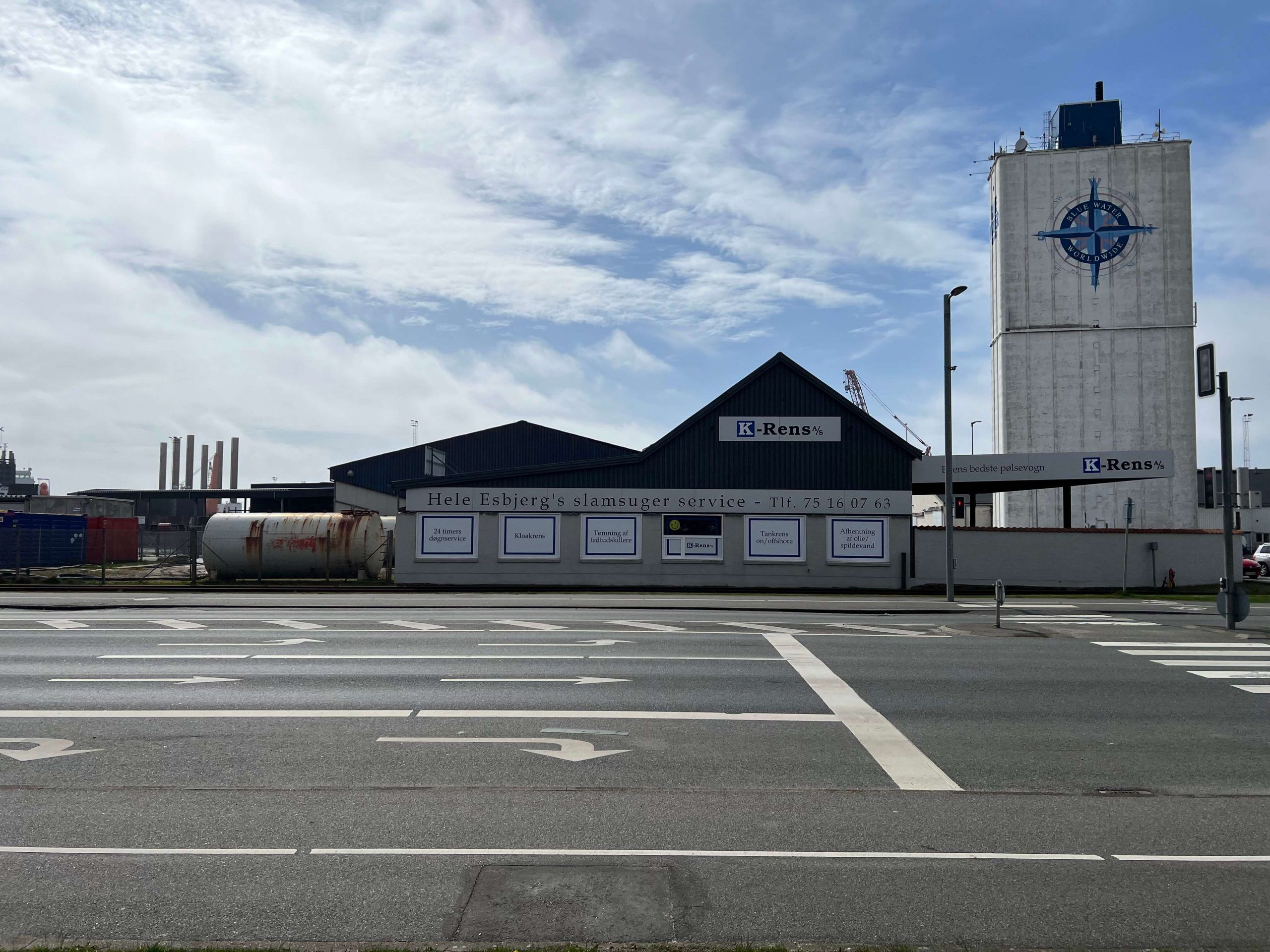 K-Rens% bygning med tårn i baggrunden og skilte med information om slamtømming og rengøringstjenester