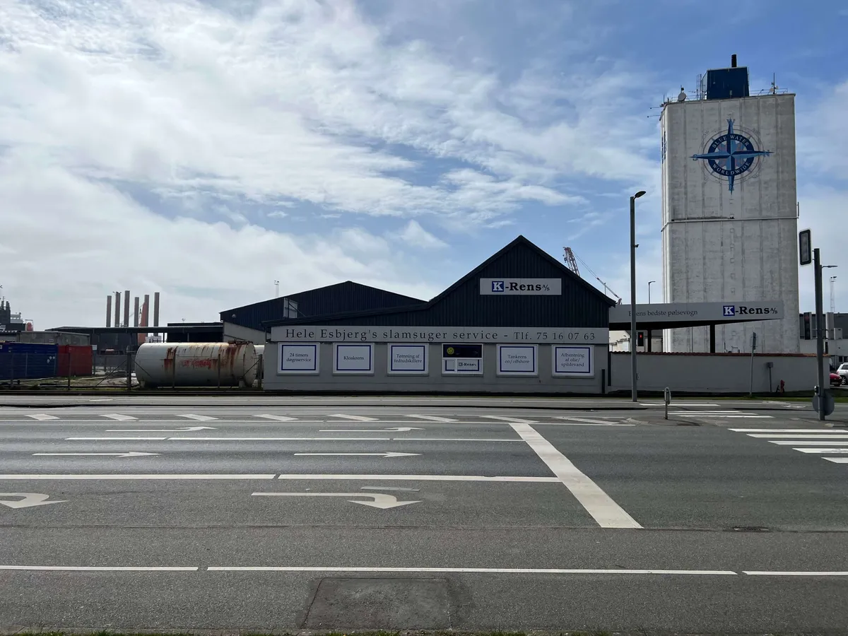 K-Rens% bygning med tårn i baggrunden og skilte med information om slamtømming og rengøringstjenester