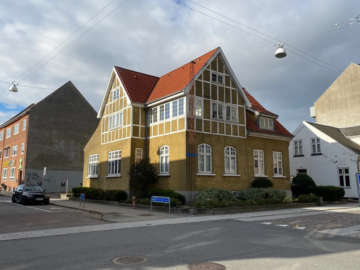 en gade med en gul bygning med rødt tag, en rødt brandhydrant og en gul stribet skilt med teksten Borgergade