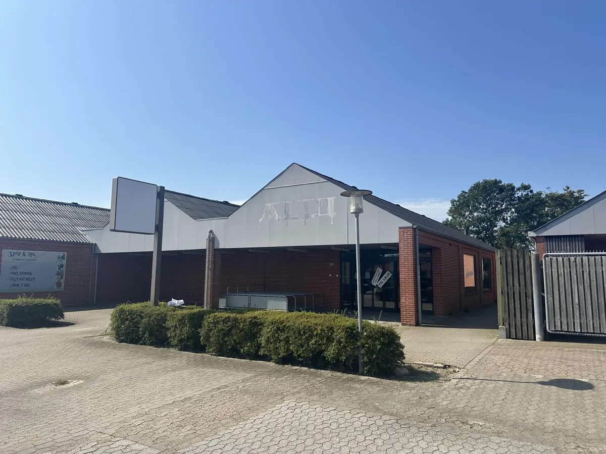 En rødmalet murstensbygning med nummer 20 på facaden. På facaden er der et reklameskilt med teksten Snow & Spil. Der er et