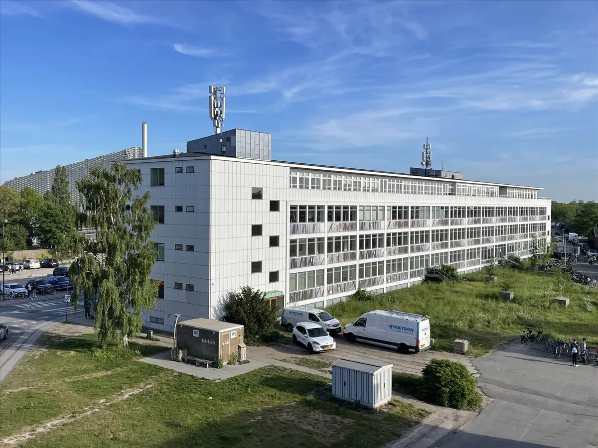 Kontorbyggeri med to biler parkeret foran og flere cykler lægges langs siderne af gården