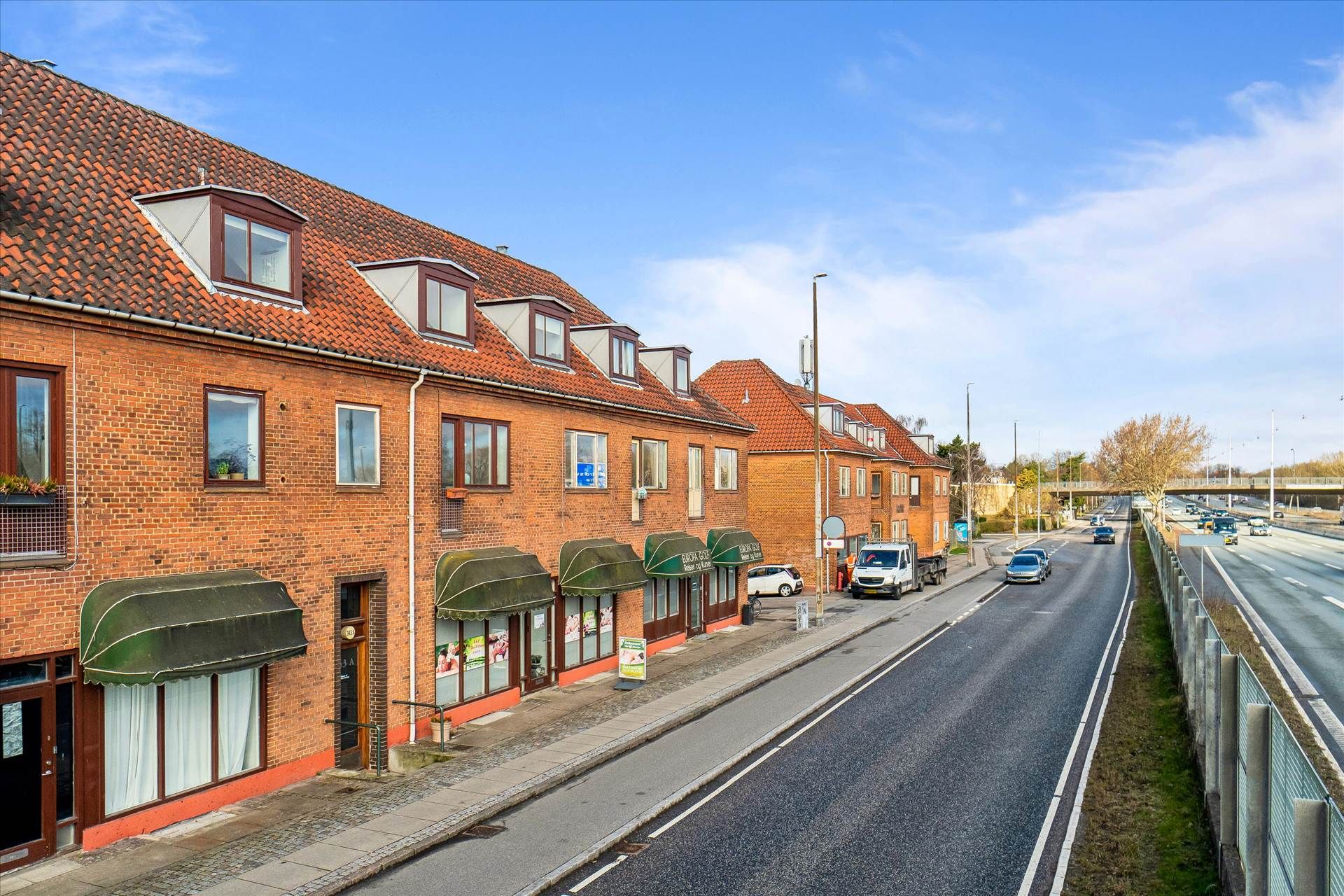 Investeringsejerlejlighed med store ruder og grønne gardiner på en fredelig gade i København
