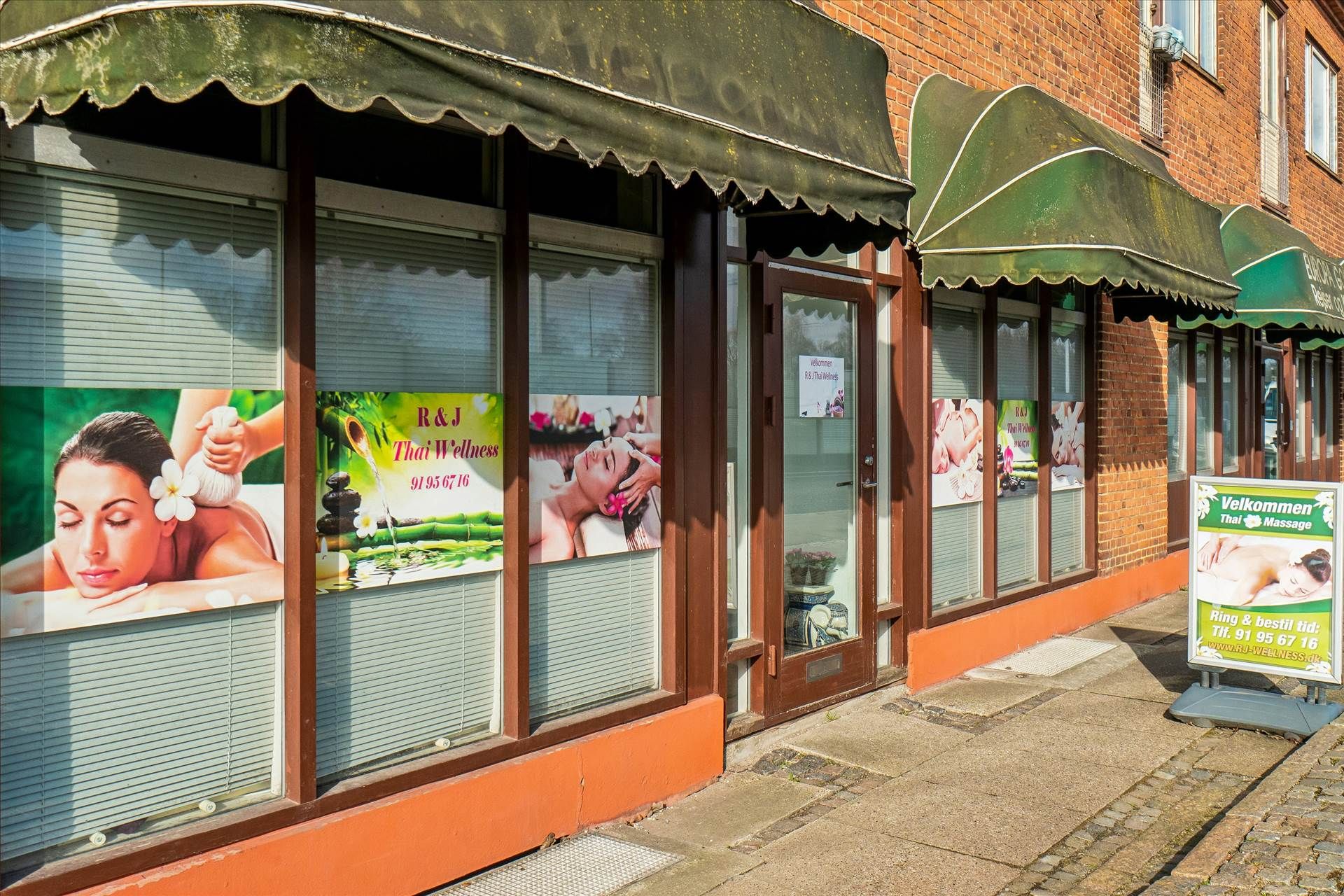 En Thai Wellness-salon med annoncer og reklameskilte udenfor, der er åben og inviterende for forbipasserende