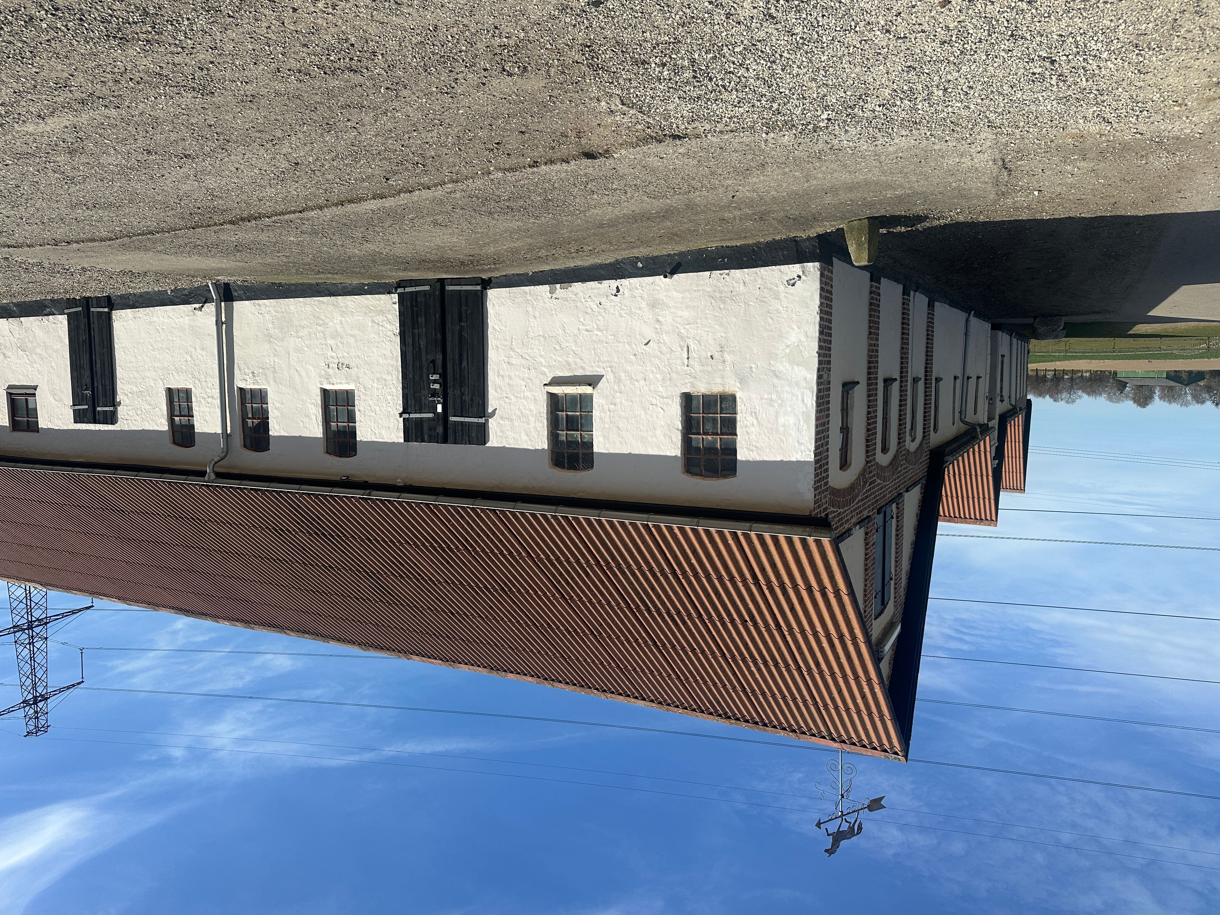 Lagerbygning med lyserøde taglejer og hvide vægge. 11 vinduer og 2 store døre. Vinduerne er udstyret med glasrute.