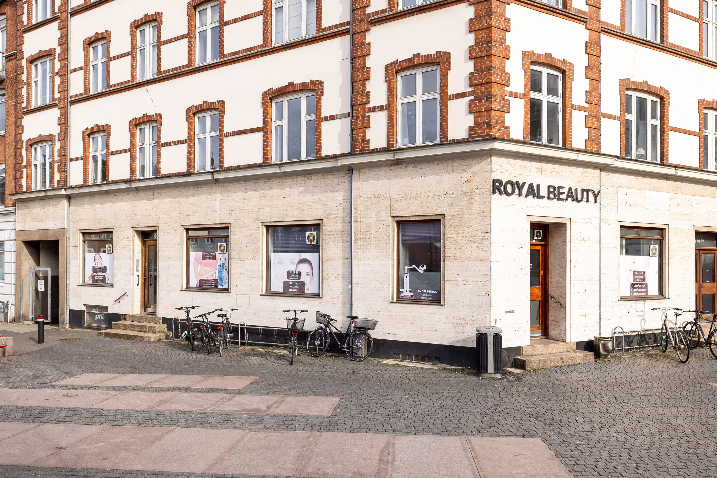 Forretning Royal Beauty ligger på Frederiksbjerg Torv i Aarhus C, med flere cykler parkeret foran. Forretningen har vinduer