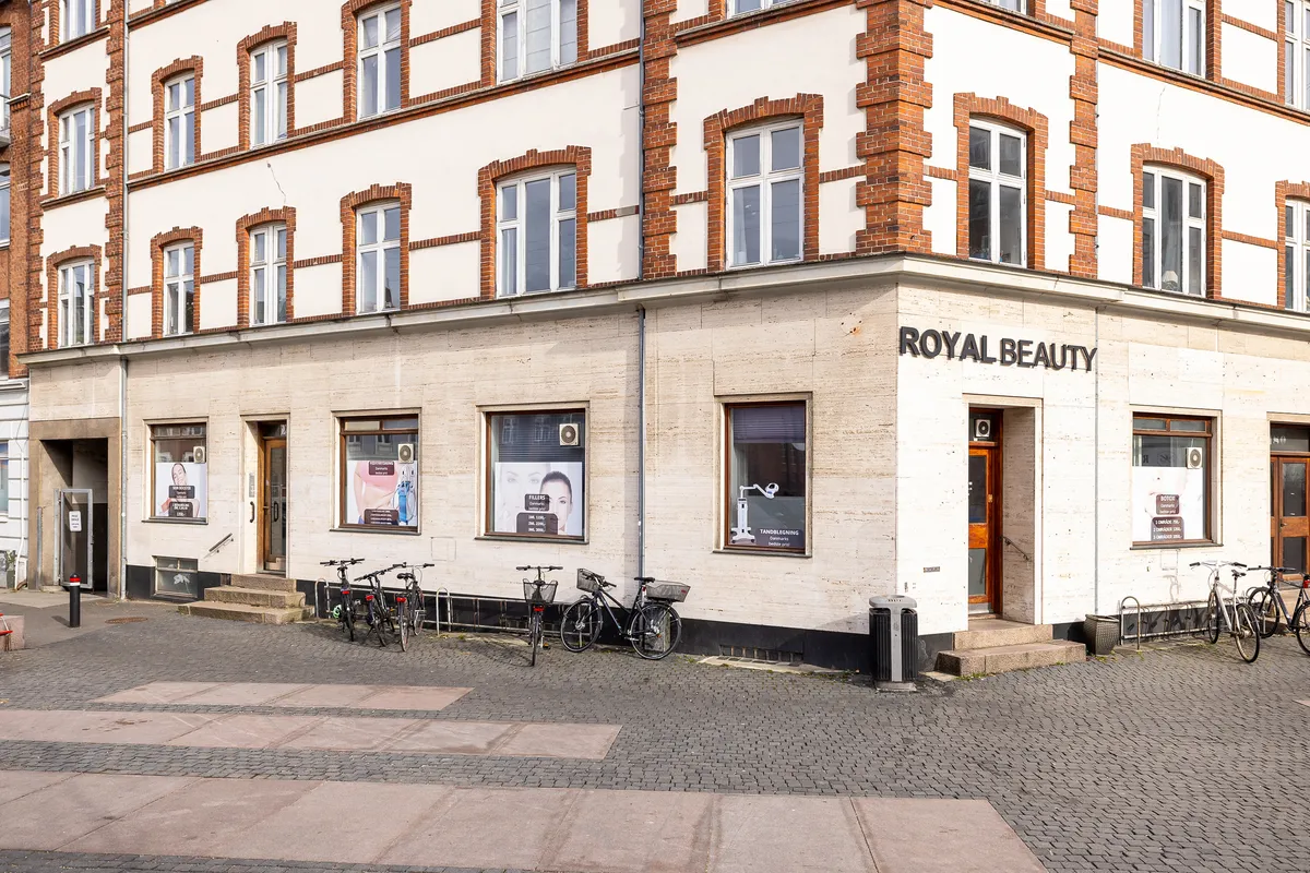 Forretning Royal Beauty ligger på Frederiksbjerg Torv i Aarhus C, med flere cykler parkeret foran. Forretningen har vinduer