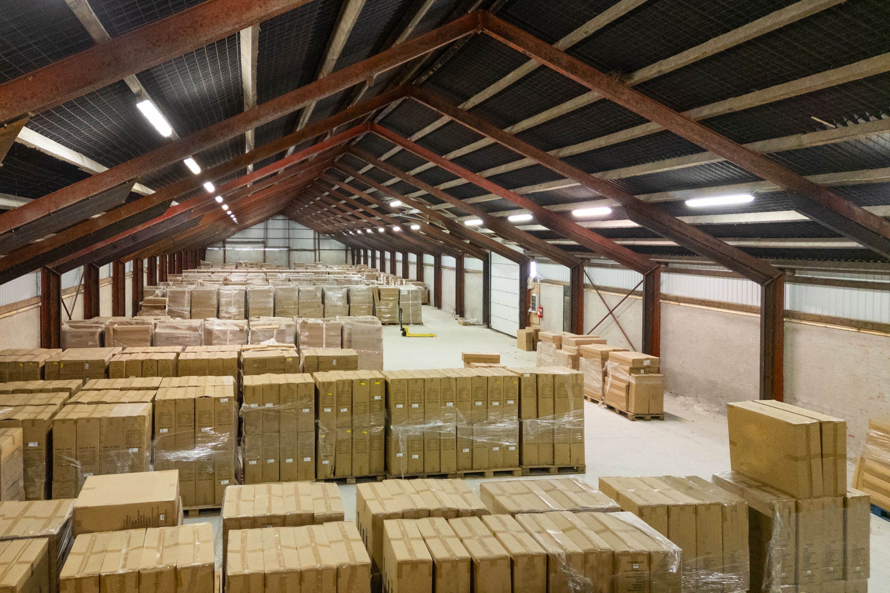 Lagerhal med lagerkasser i rækker og rækker og røde bjælker under loftet