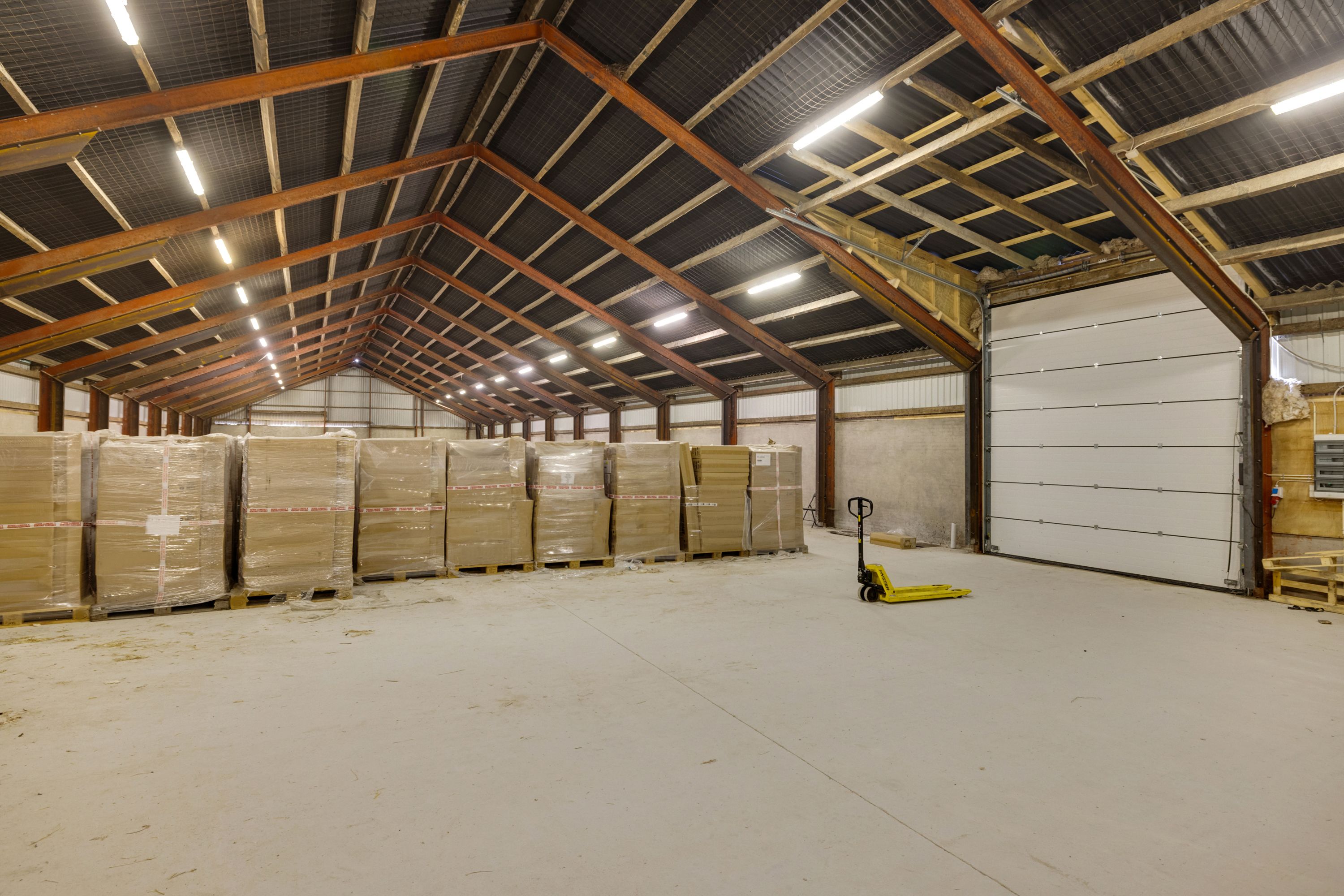 Lagerhal med masser af forskellige pakker og en gaffeltruck parkeret i forgrunden