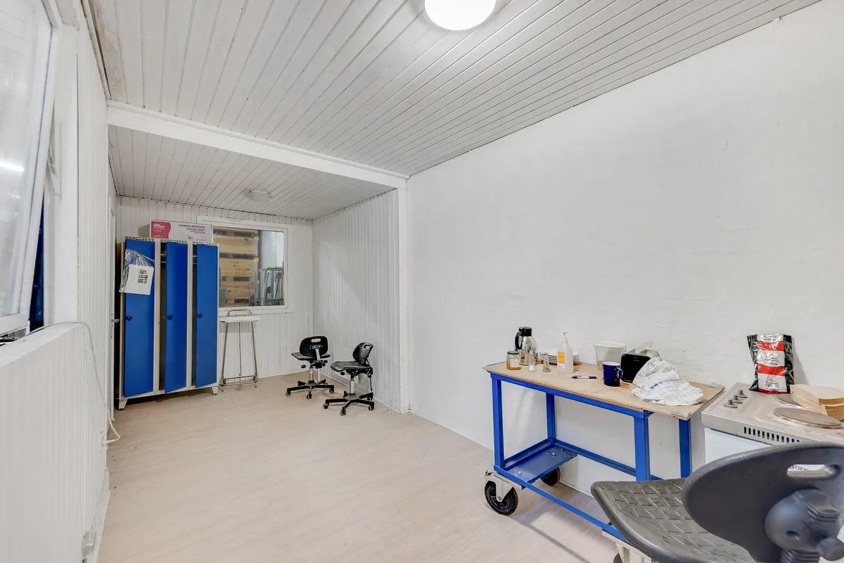 Renset og pænt lokale med to høje blå skabe og en høj skrivebord med flere genstande og en stol med hjul.