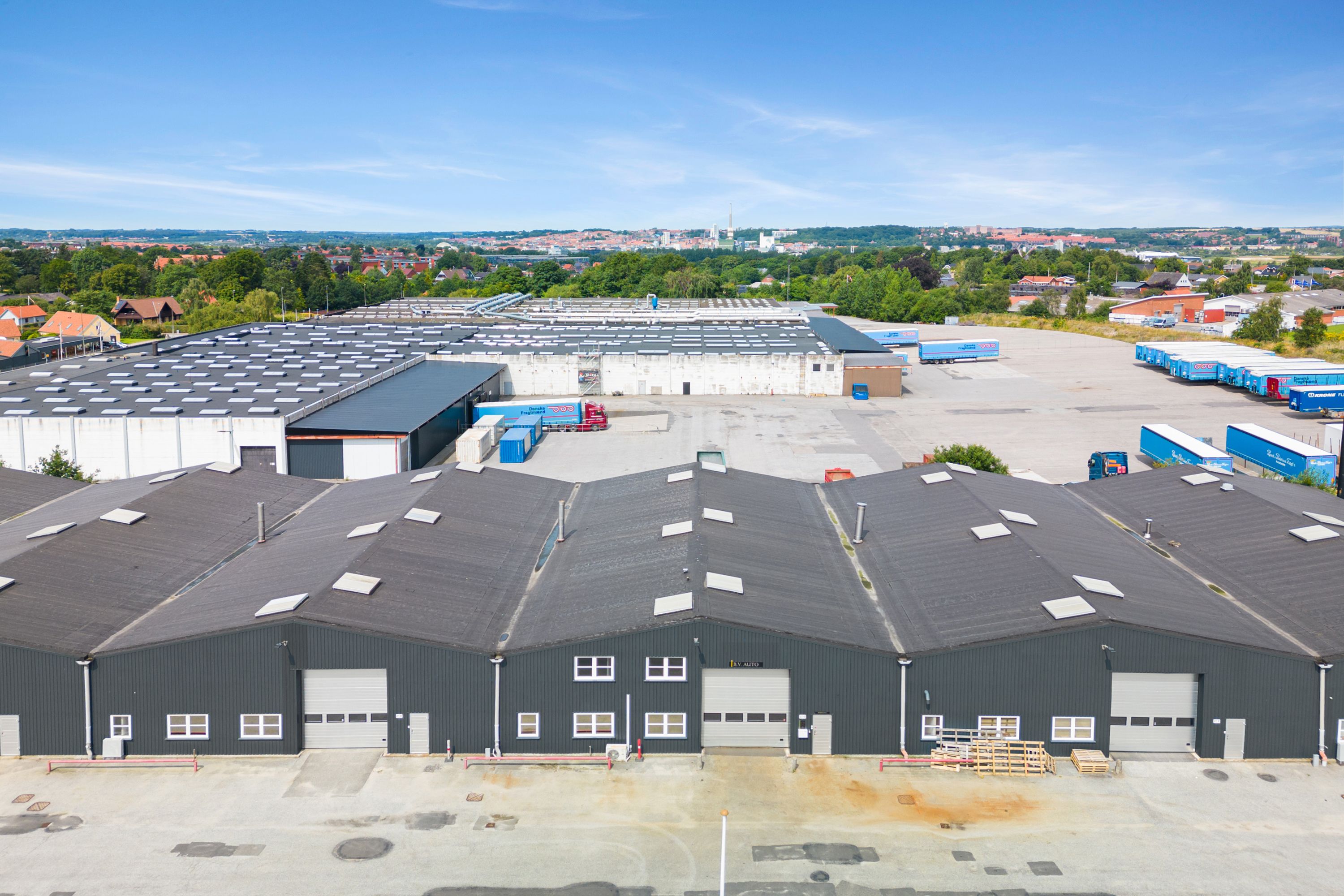 et stort industrikompleks med flere bygninger og fraktbiler parkeret udenfor i Randers Syd