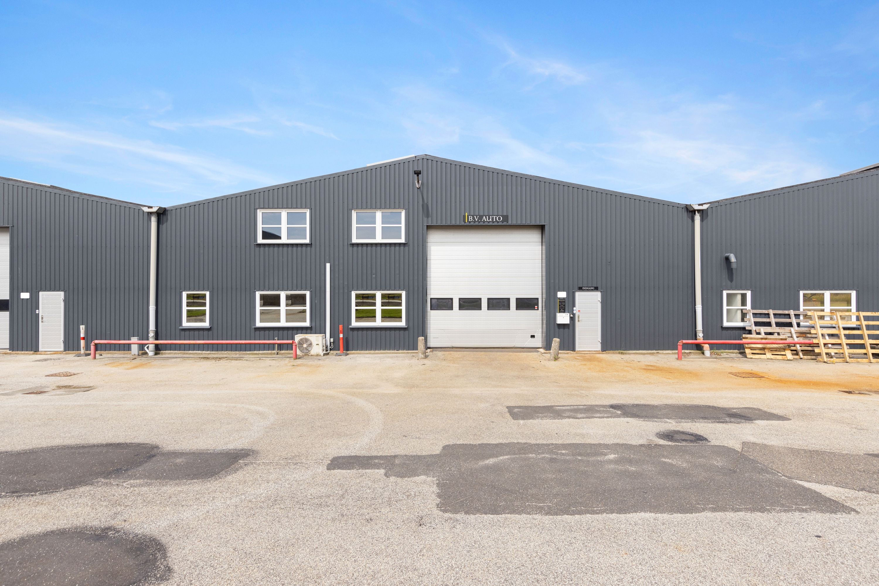 Et industrielt bygningskompleks med store garagedøre og mange vinduer med teksten B.V. Auto