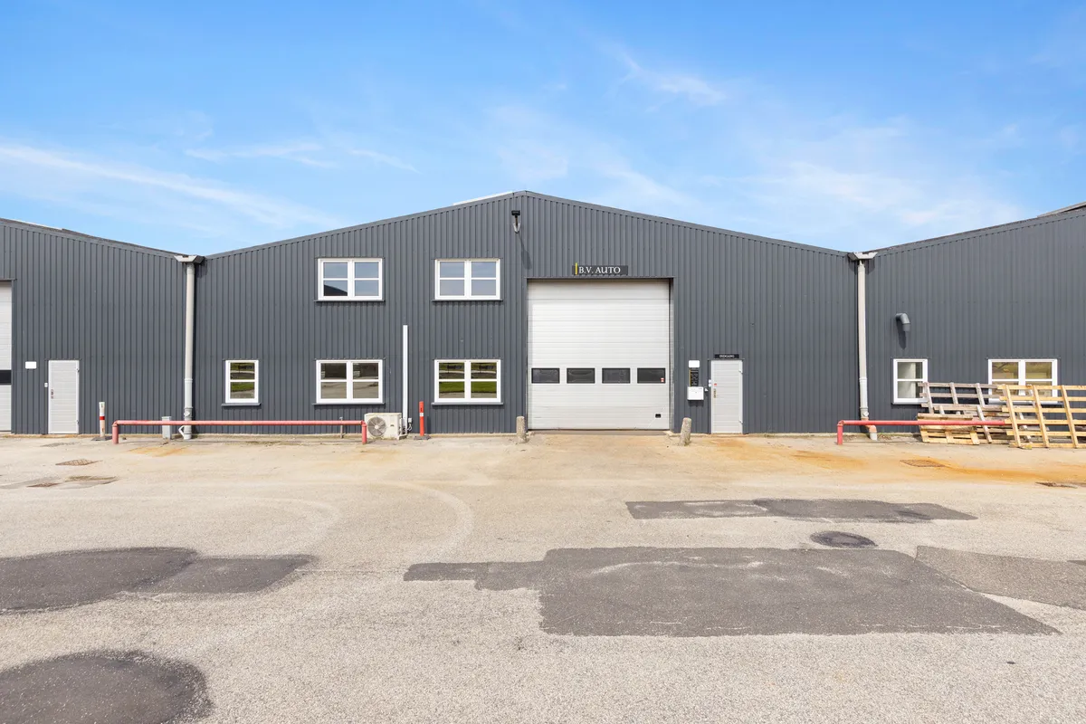 Et industrielt bygningskompleks med store garagedøre og mange vinduer med teksten B.V. Auto