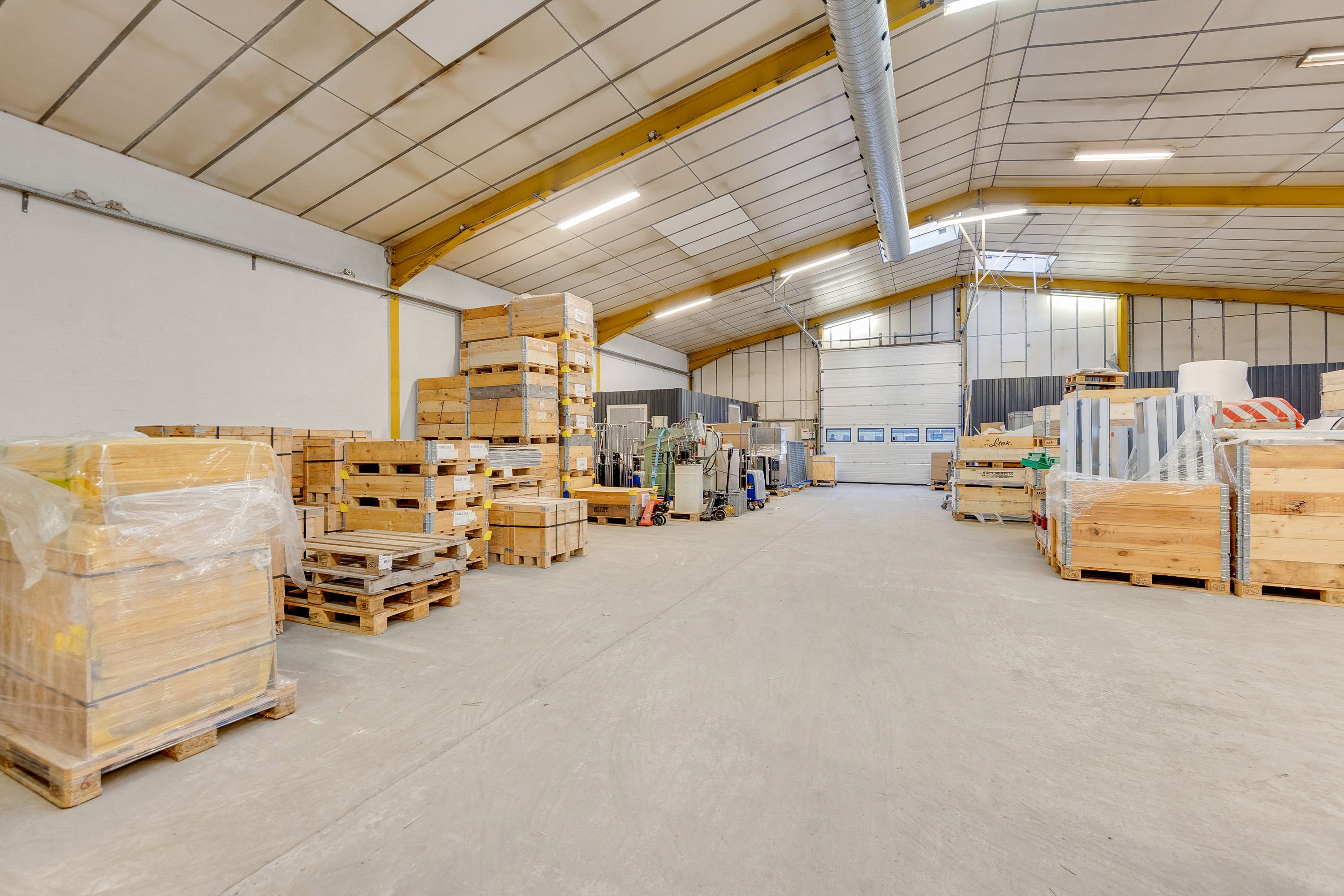 En stor lagerhal med mange pakketømmerkasser og flere mærker af fabriksudstyr.