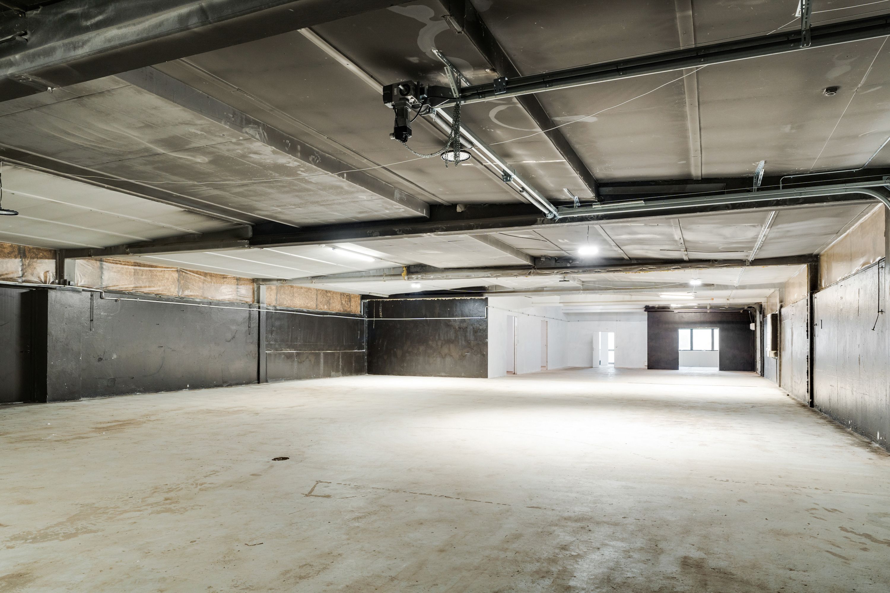 En stor, tom garage med højt loft, store døre og belysning på loftet