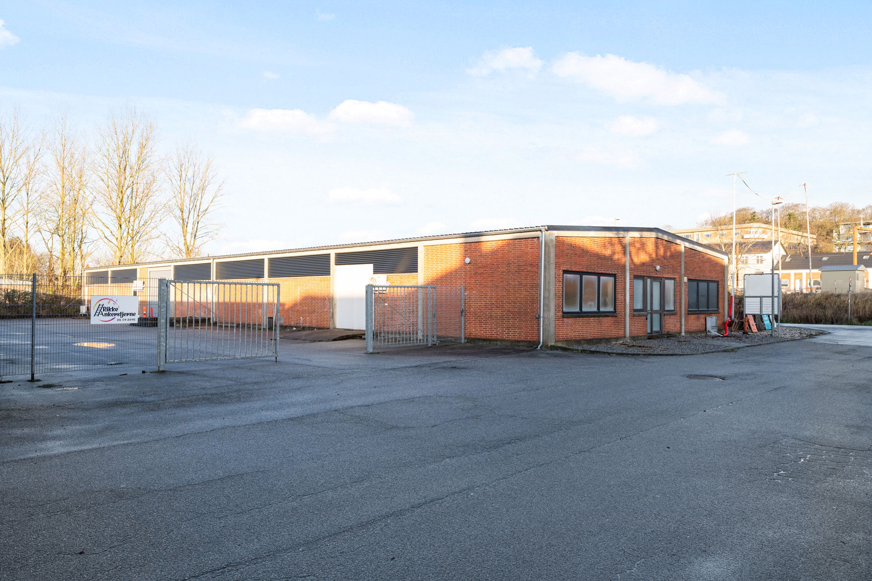 Lager og kontorer til leje i Horsens, med indgangsdøre og en stor, tom parkeringsplads