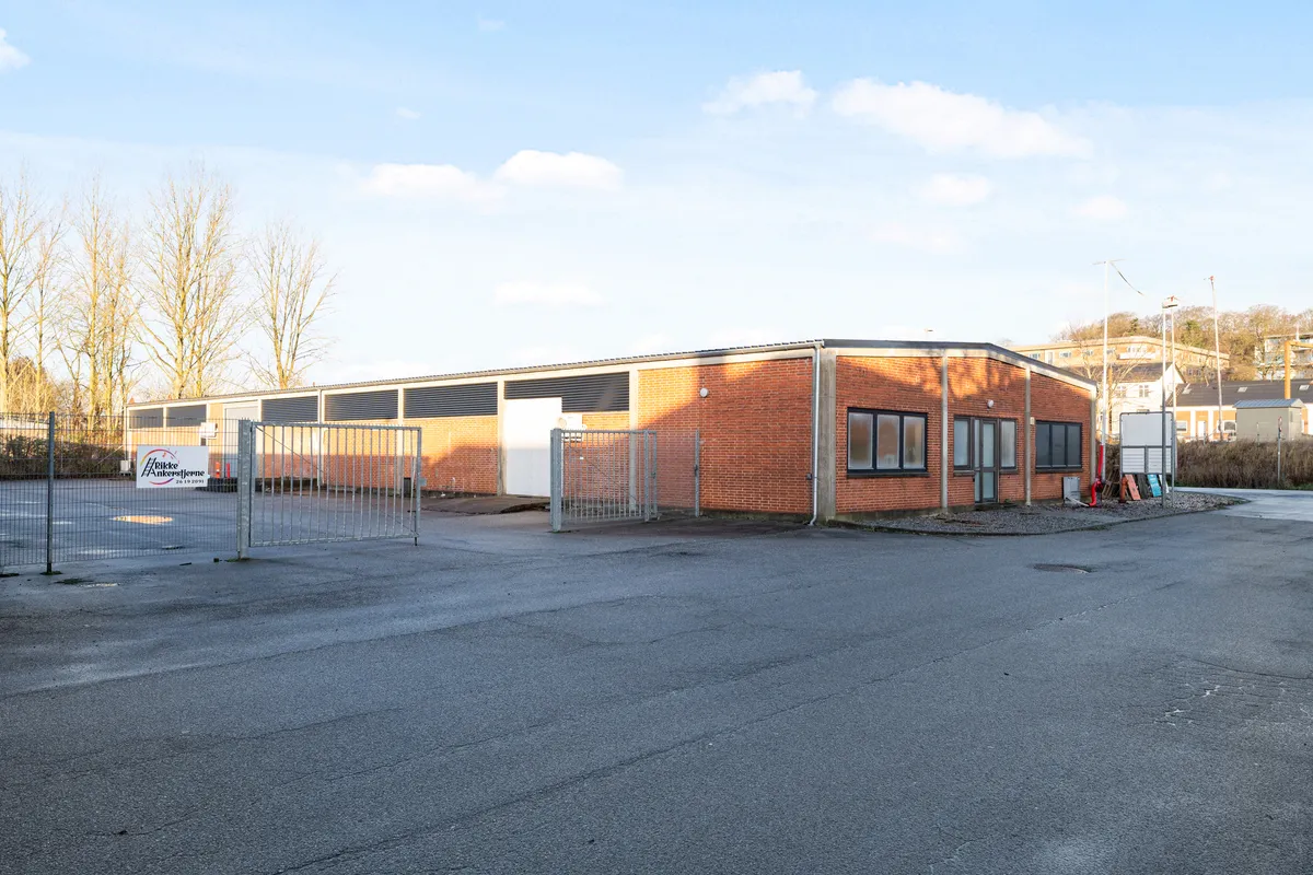 Lager og kontorer til leje i Horsens, med indgangsdøre og en stor, tom parkeringsplads