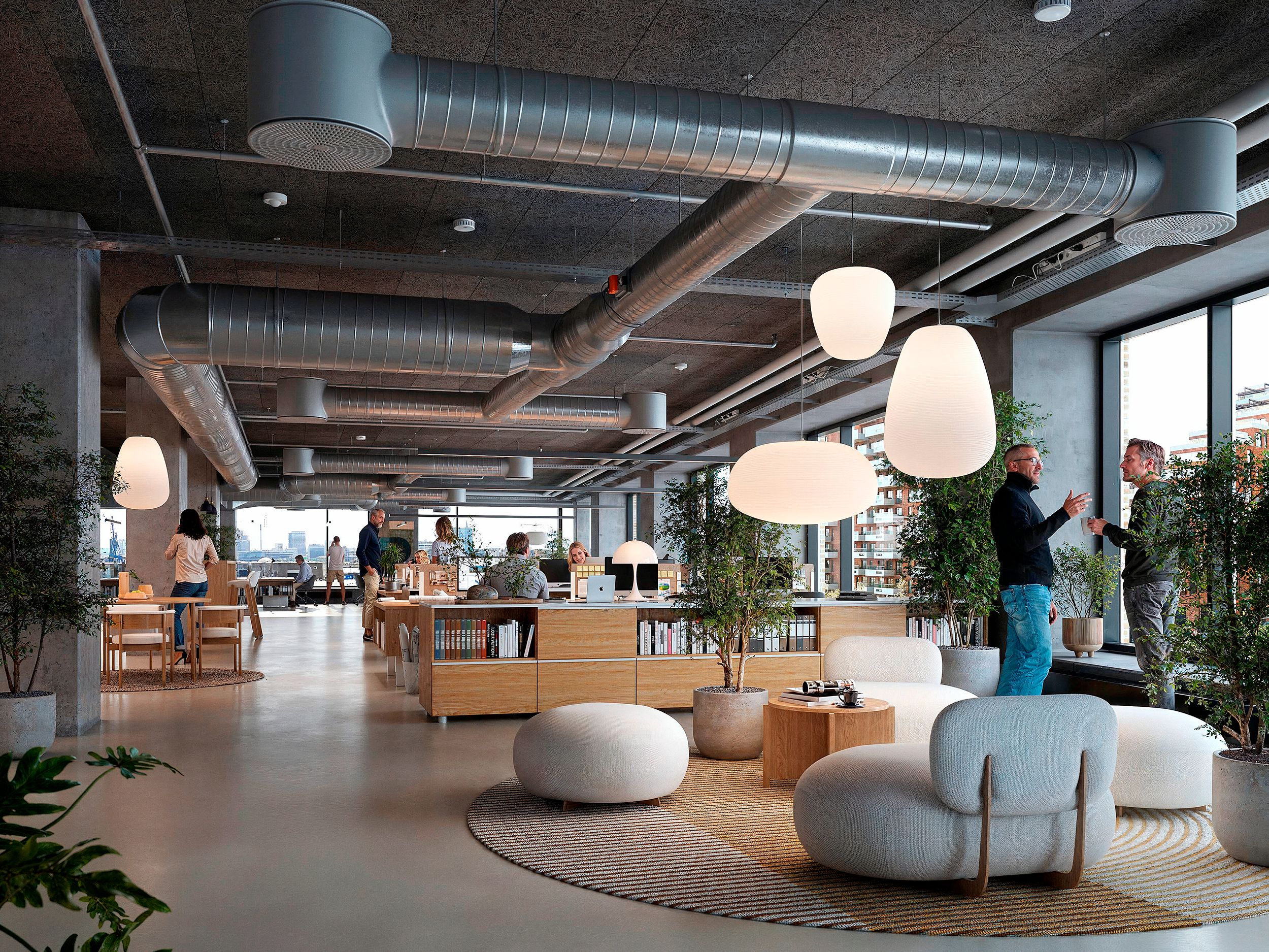 Kontorområde med store lysekroner, lyse kanterne, runde hvide lænestol og et stort bibliotek med bøger