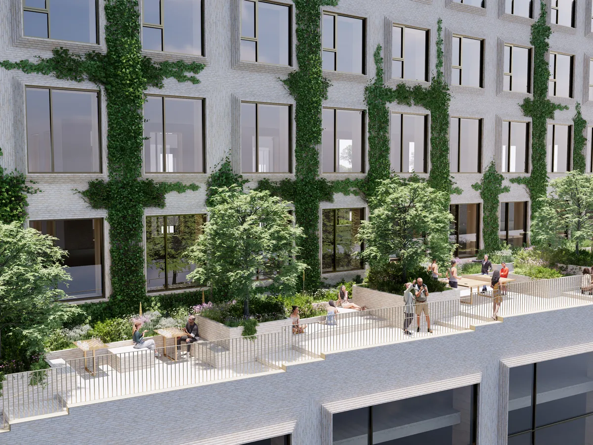 Mange mennesker mødes på en terrasse med planter og træer på en nyopført bygning med glasvinduer og grønne vægbeklædninger