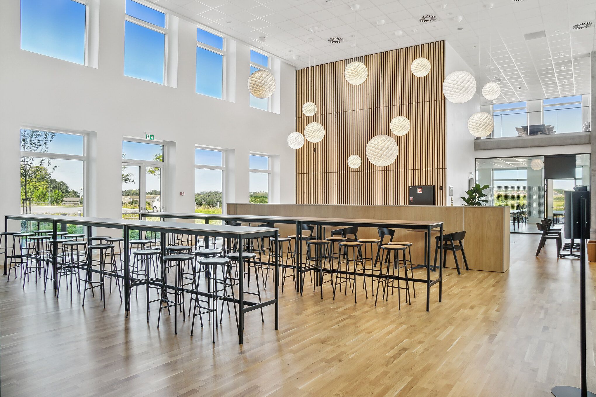 Indvendørs er der en stor lobby med store vinduer, lys gulv og lyse loftslamper