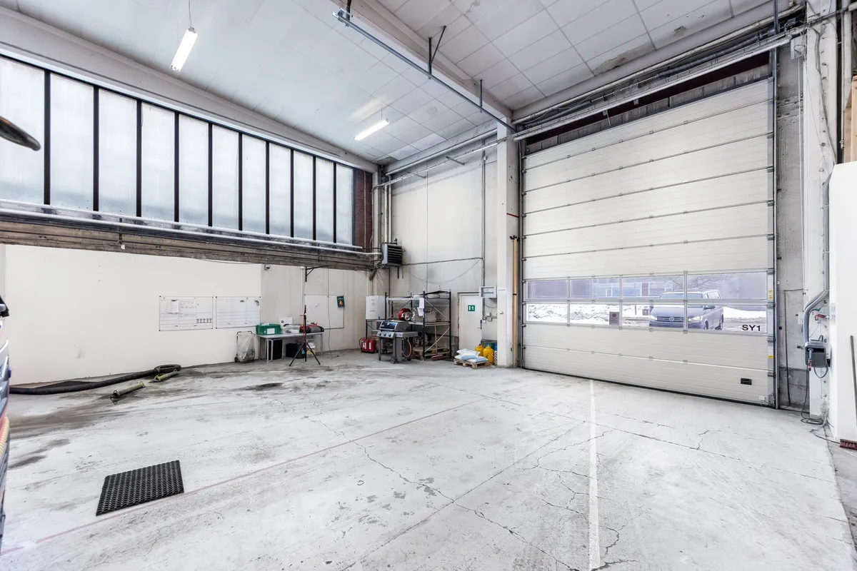 Lager med administrationslokaler og garageporte. Mange lyse og store vinduer. Forskellige værktøjer og materialer på plads.