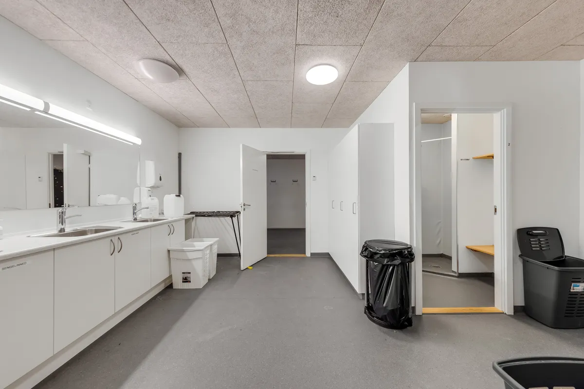 Rent og renseri lager med lyse lofter og hvide vægge, der er to åbne døre og en stor skraldspande med skraldeposer og