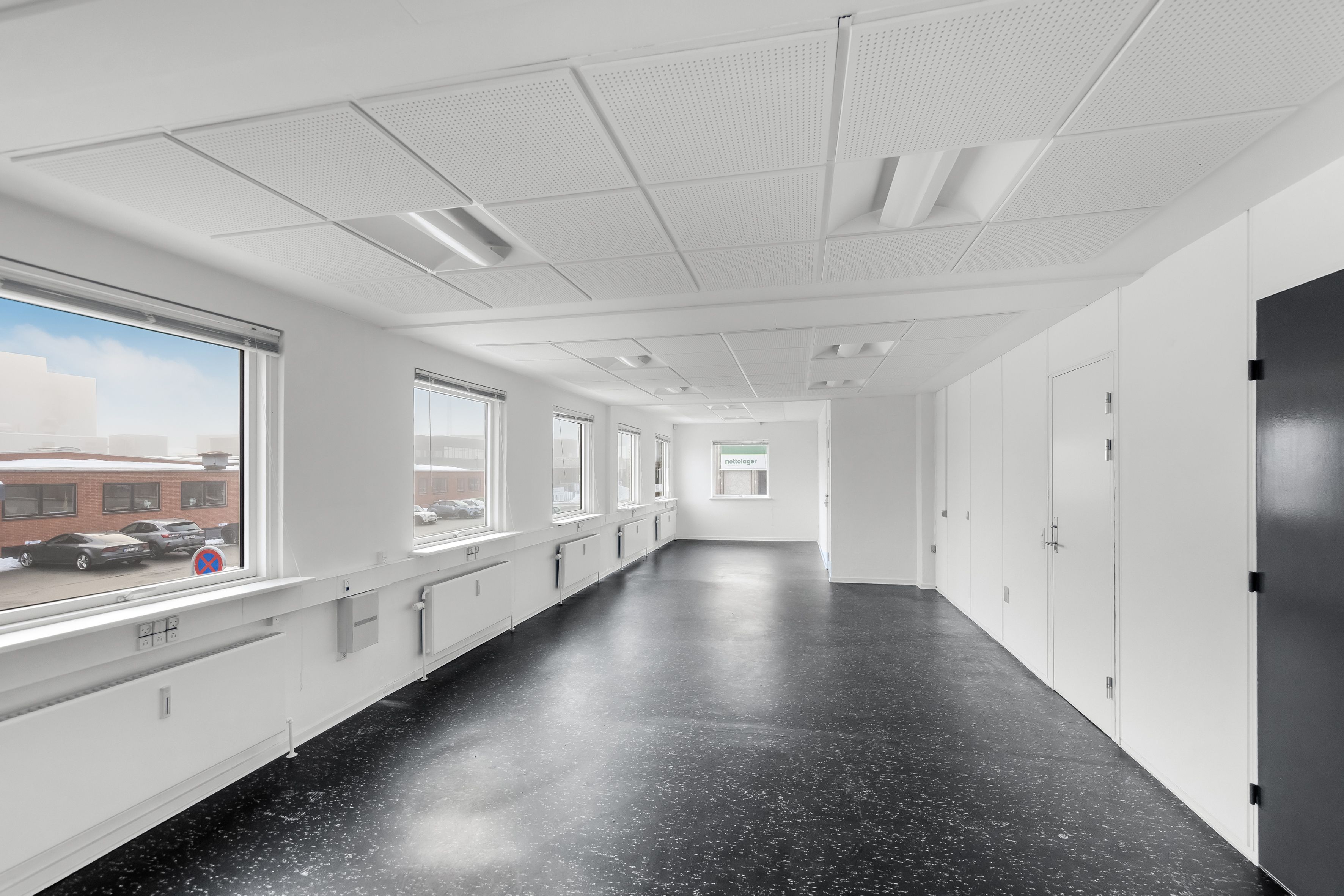 Et lager med porte og højloft. Højloftet lager med vinduer og gulve af sort granit. Højloftet lager med flere hvide vægge og