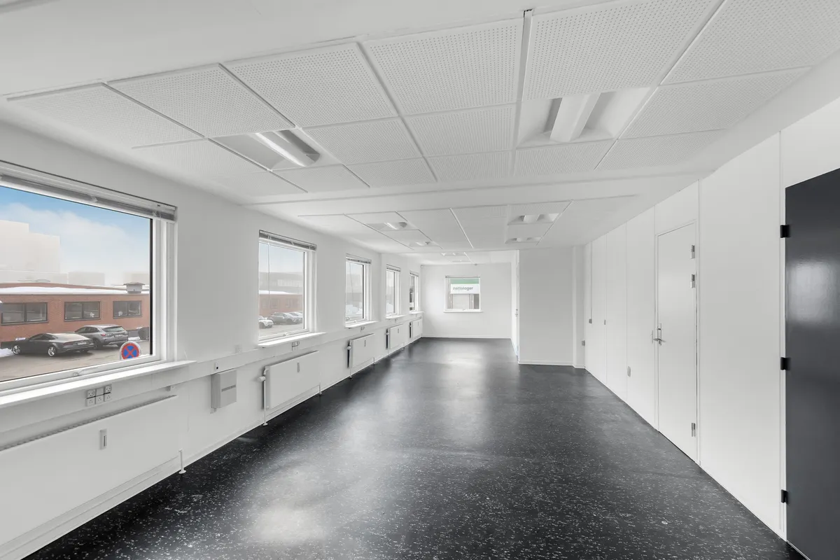 Et lager med porte og højloft. Højloftet lager med vinduer og gulve af sort granit. Højloftet lager med flere hvide vægge og