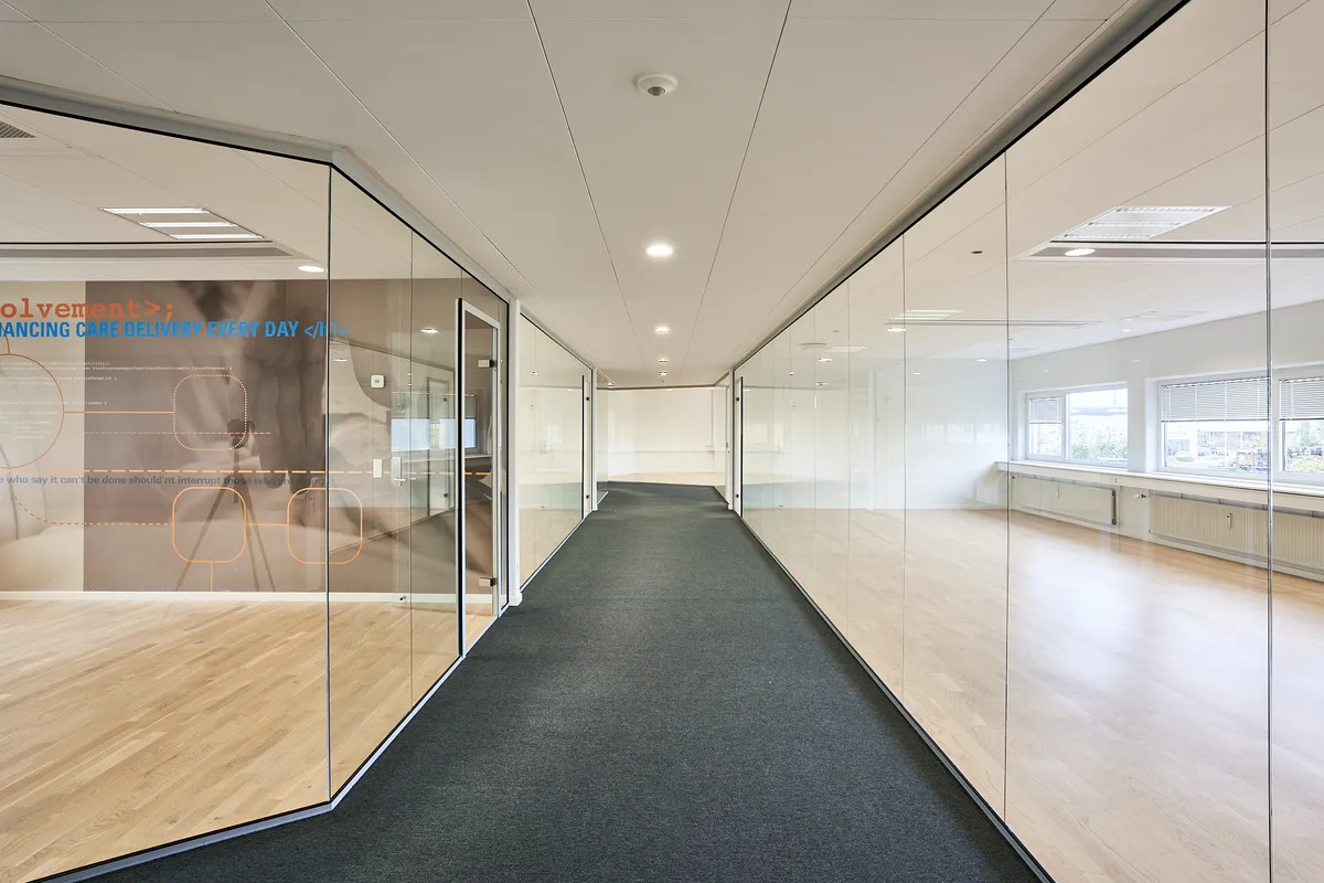 En stor hall med glasvægge og gulvtæppe i midten, hvor der er en væg med tekst og billeder